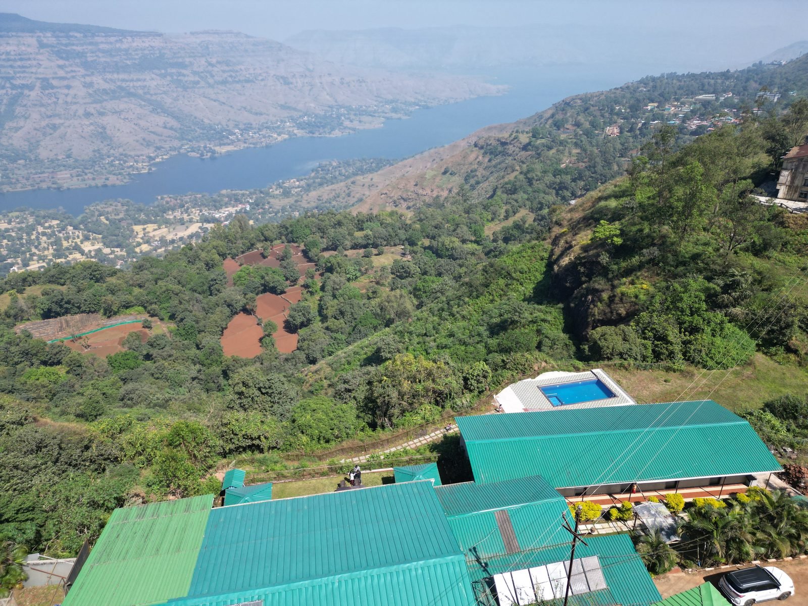 Aerial view of Krishna Valley Resort with swimming pool and lake backdrop, Panchgani